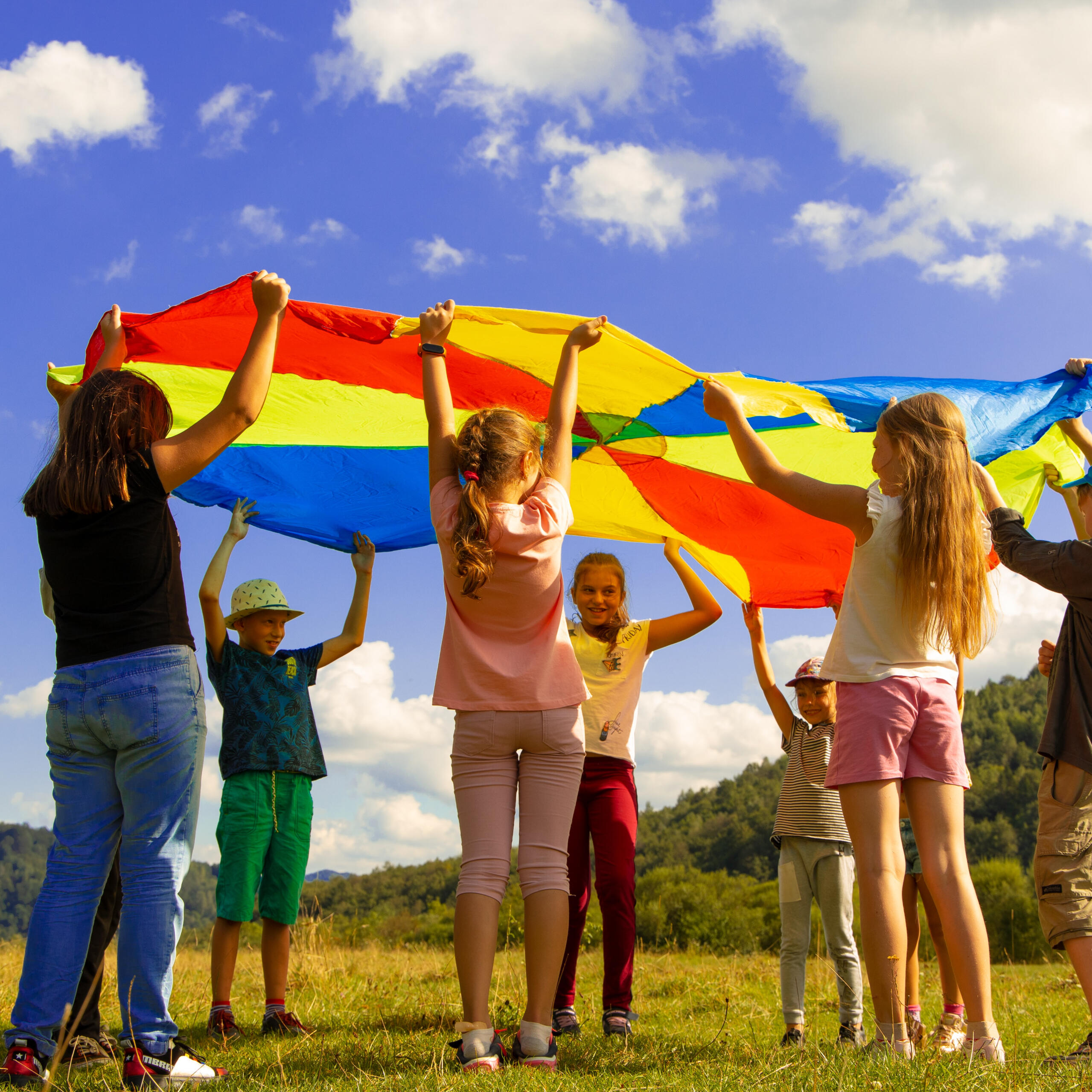 Kids in an open field playing a parachute game